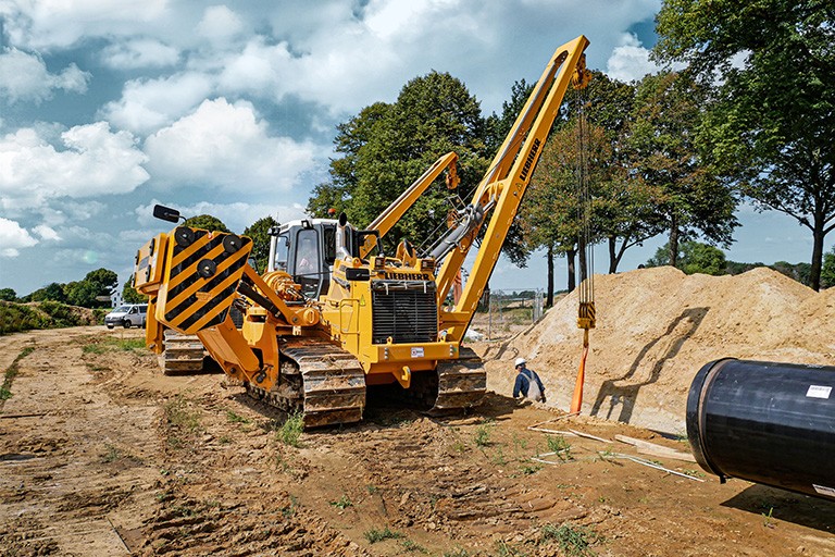 MAATS Liebherr pipelayer lifting and positioning pipeline section at construction site.